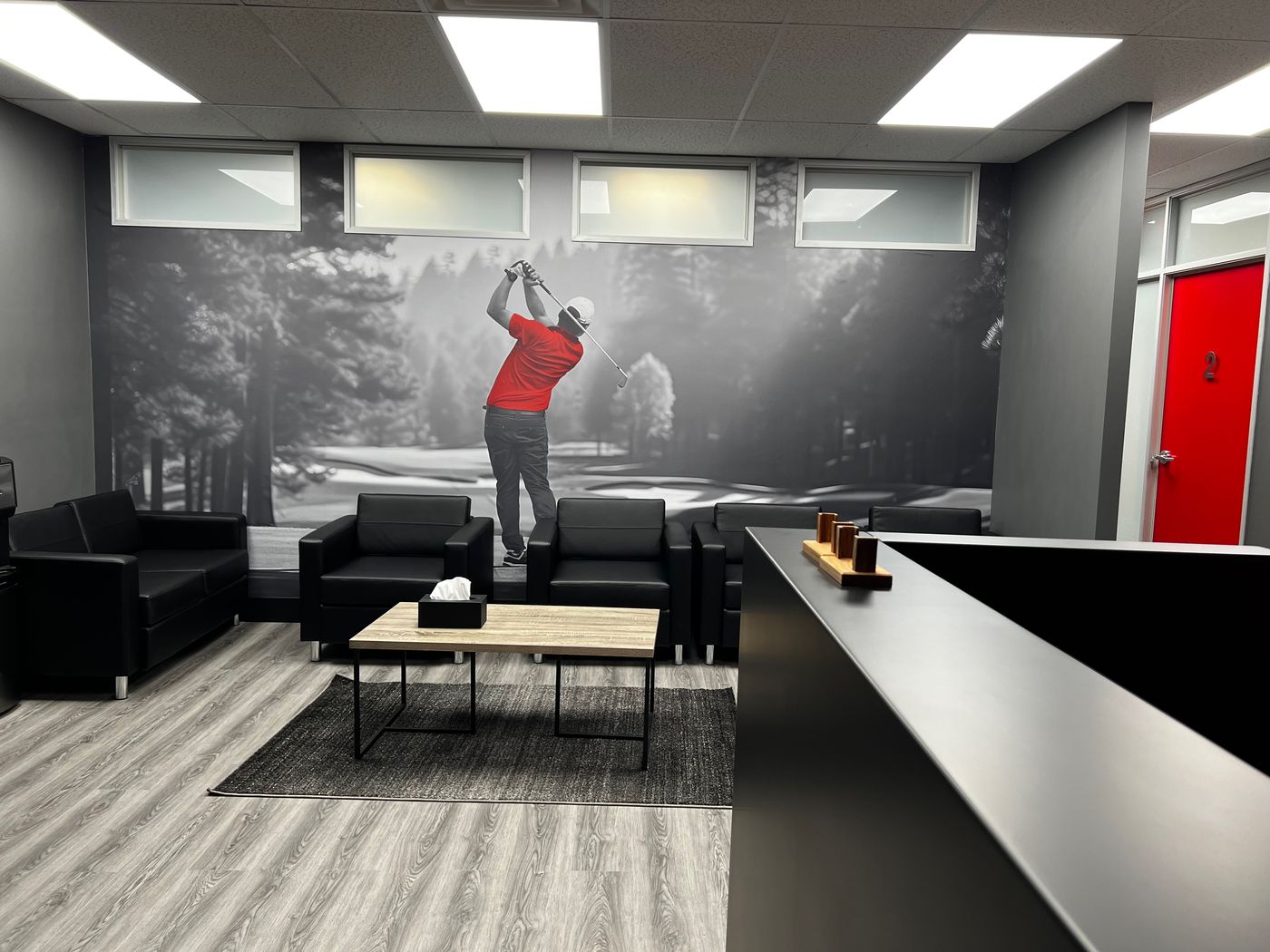 Waiting lounge at Game Day West Oakville with leather seating and golf mural — more lounge than doctor's office